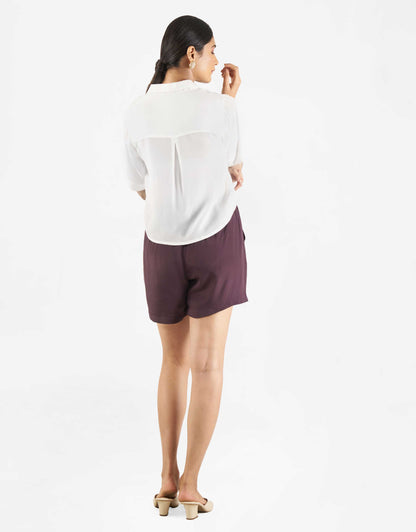 Back view of Hueloom's sure shot capsule with boxy shirt and shorts in white and purple.